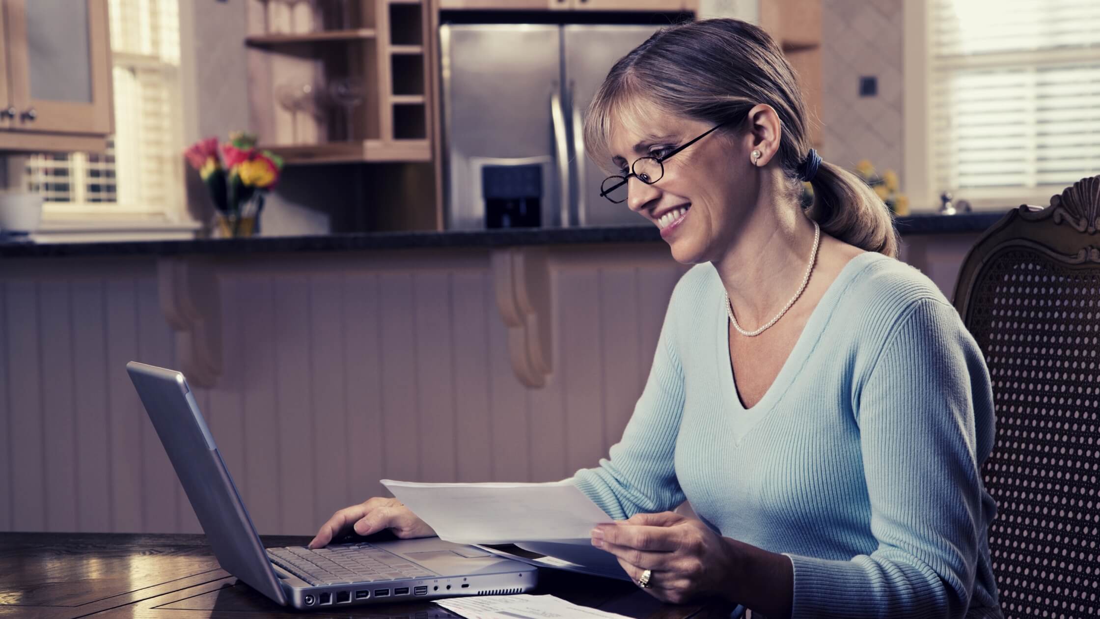 Mujer adulta con lentes trabajando en su laptop